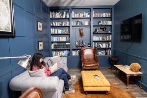 a woman sitting on a couch reading a book at Domaine de charme pour groupes et evenement in Chillac