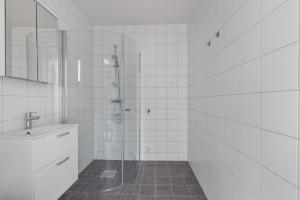 a white tiled bathroom with a shower and a sink at Ekenäs Havshotell Koster in Sydkoster +30 photos