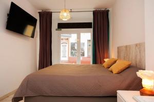 a bedroom with a bed and a tv and curtains at Loft Valentia Ifach Calpe in Calpe