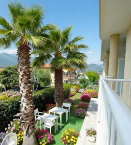 a balcony with palm trees and tables and flowers at ALBACHIARA INN Residence Apartments in Ameglia