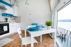 una cucina bianca con tavolo e balcone di -Ortaflats- Appartamento Gli Archi a Orta San Giulio