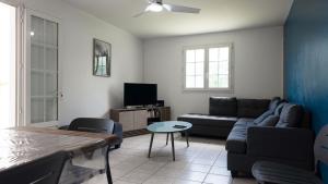a living room with a couch and a table at Villa kréoli avec picine privée et cuisine extérieur pour 8 personnes in Saint-André