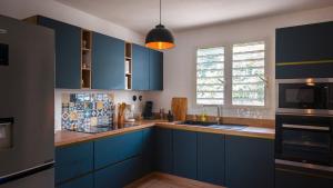a kitchen with blue cabinets and a sink and a window at Villa kréoli avec picine privée et cuisine extérieur pour 8 personnes in Saint-André