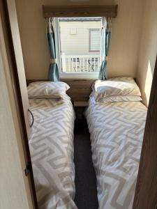 two beds in a small room with a window at TLJ Caravan Hires in Mablethorpe