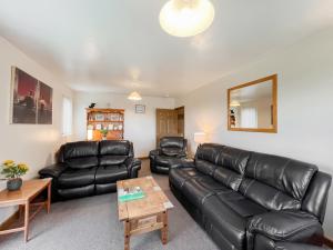 a living room with a leather couch and a table at Uk47550 - Cairnsmore Cottage in Newton Stewart