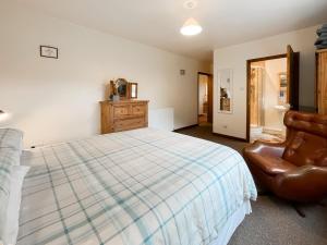 a bedroom with a bed and a leather chair at Uk47550 - Cairnsmore Cottage in Newton Stewart +11 photos