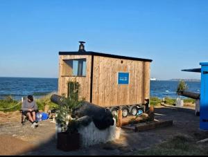 a woman sitting on a bench in front of a tiny house at Sea Breeze in Wexford
