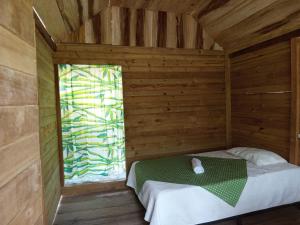 a bed in a wooden room with a window at Cabaña y restaurante vikana in Nuquí