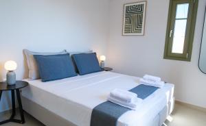 a white bedroom with a large bed with blue pillows at Villa Selina 7 - Etheras Properties in Kythira +49 photos