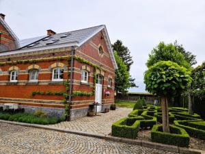 a brick building with a tree in front of it at Station Racour 'Magasin de la gare' in Landen +20 photos