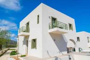 a white building with green doors and balconies at Villa Selina 7 - Etheras Properties in Kythira