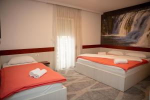 a bedroom with two beds and a painting of a waterfall at Villa Bojcic in Mostar
