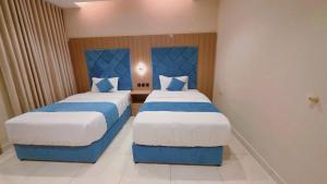 a bedroom with two beds with blue and white sheets at الديار الفاخرة - احد رفيدة in Ahad Rafidah