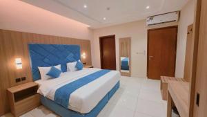 a bedroom with a large bed with a blue headboard at الديار الفاخرة - احد رفيدة in Ahad Rafidah