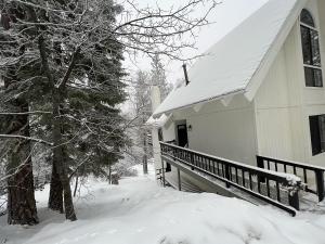 a house with a snow covered porch next to a tree at Brentwood Haus in Lake Arrowhead