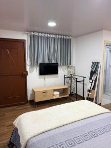 a bedroom with a bed and a flat screen tv at Mini centrica suite privada con todo incluido in Loja