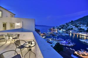 a balcony with tables and chairs and a view of a harbor at Onar Hydra in Hydra +54 photos