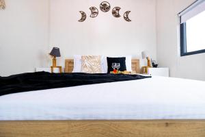 a bedroom with a large white bed with black sheets at The HIDE - Dreamland in Boldeşti-Scăeni