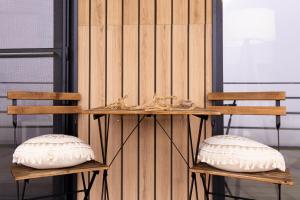 two wooden chairs with pillows on them next to a wall at The HIDE - Dreamland in Boldeşti-Scăeni