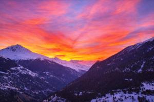 a sunset over a mountain range with mountains at Maison d'Hortense - Chalet le Renard in Hérémence +3 photos