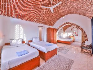 a bedroom with two beds and a brick wall at Beit El Hanna Valley View in Luxor