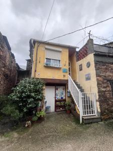 a yellow house with a staircase in front of it at A casa do teléfono in Pumares