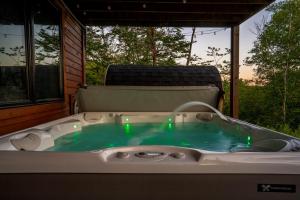 a hot tub on a porch with green lights in it at Epic Views, 9Mi SR, GameRmTheater, HTub, Sauna in Bethel +69 photos