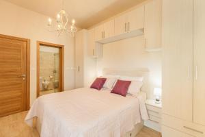 a bedroom with a white bed with purple pillows at Urban Vista Residence in Španjola