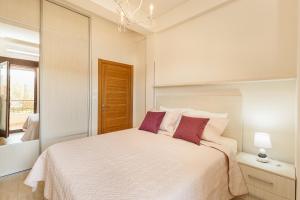 a bedroom with a large white bed with purple pillows at Urban Vista Residence in Španjola