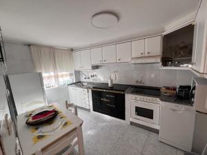 a kitchen with white cabinets and a black stove top oven at A casa do teléfono in Pumares
