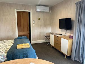 a bedroom with a bed and a dresser with a television at Kotahi Cottage in Cambridge