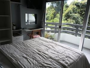 a bedroom with a bed and a large window at Tree Top Beach Condo in Ban Pak Khlong Phe