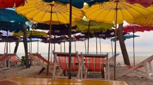 a group of chairs and umbrellas on a beach at Tree Top Beach Condo in Ban Pak Khlong Phe