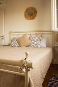 a white bed with pillows and a mirror on the wall at Villa Aristidis Strates in Argyrádes