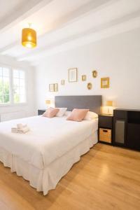 a white bedroom with a large white bed with pink pillows at La maison aux 5 nids in Saint-Cyr-sur-Loire