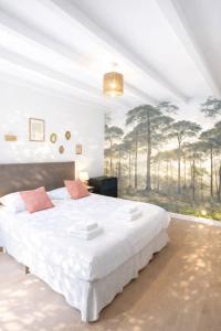 a bedroom with a large white bed with a painting on the wall at La maison aux 5 nids in Saint-Cyr-sur-Loire