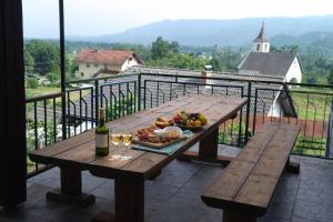 a wooden table with a bowl of fruit and a bottle of wine at Apartmaji Marko in Bled
