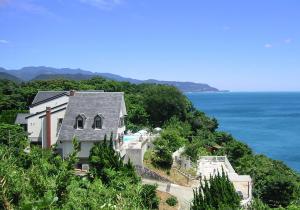 a house on a hill next to the ocean at Gardenvilla Shirahama in Shimoda