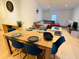 a living room with a wooden table and blue chairs at L'Emile Zola l 2 Chambres l Hypercentre in Castres