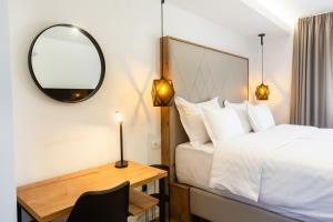 a bedroom with a bed and a desk with a mirror at The Hill Aparthotel in Mostar