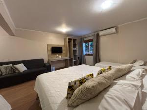 a bedroom with a large bed and a couch at Pousada Stillo Gramado Centro - 300 metros da rua coberta in Gramado