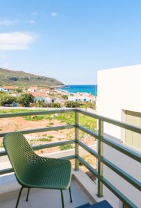 a green chair on a balcony with a view of the beach at Villa Selina 8 - Etheras Properties in Kythira