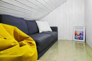 a blue couch in a living room with a yellow blanket at The HIDE - Loftette in Ploieşti
