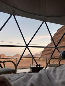 a bed in a tent with a view of the desert at Talira Luxury Camp in Wadi Rum