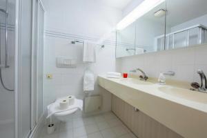 a white bathroom with a sink and a toilet at Maraini Elegante Apartment with Jacuzzi & Balcony - Happy Rentals in Lugano