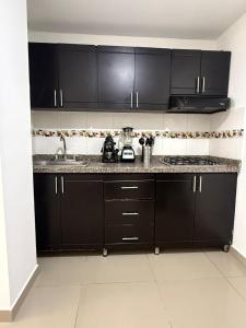 a kitchen with black cabinets and a counter top at Moderno Apto central in Estación El Salto