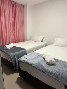 a room with two beds and a red curtain at Moderno Apto central in Estación El Salto