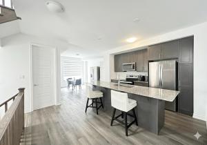 a kitchen with a counter and some chairs in it at Keppel Circle Residence in Brampton