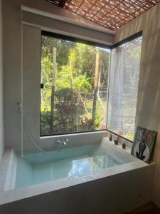 a bathroom with a bath tub with a large window at Jeribucaçu bangalô in Itacaré