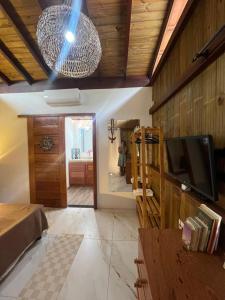 a living room with a television and a person in a bathroom at Jeribucaçu bangalô in Itacaré